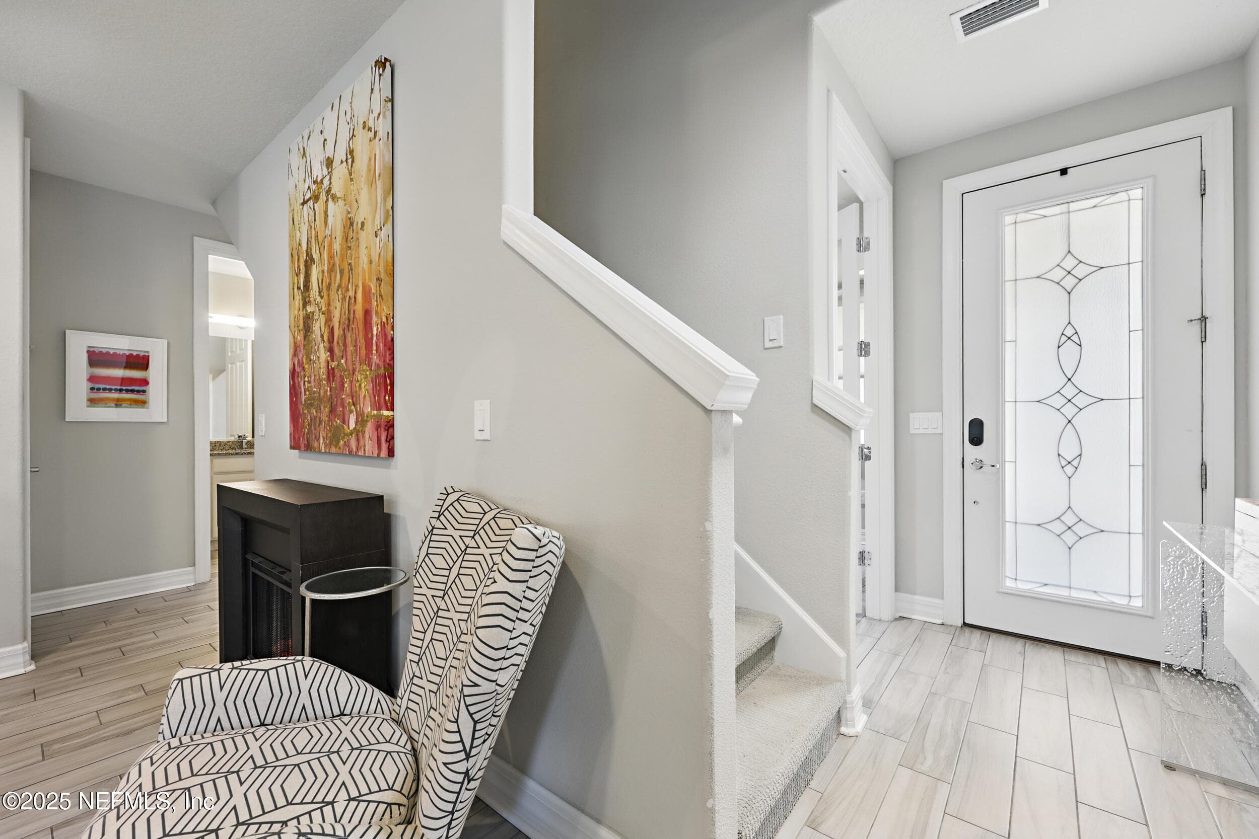 Foyer and staircase — Two-story foyer with decorative leaded glass front door, wood-look tile flooring, carpeted staircase with white painted railing and newel post, and neutral gray walls with white trim throughout. — 92 CANOPY OAK Lane, Ponte Vedra, FL 32081