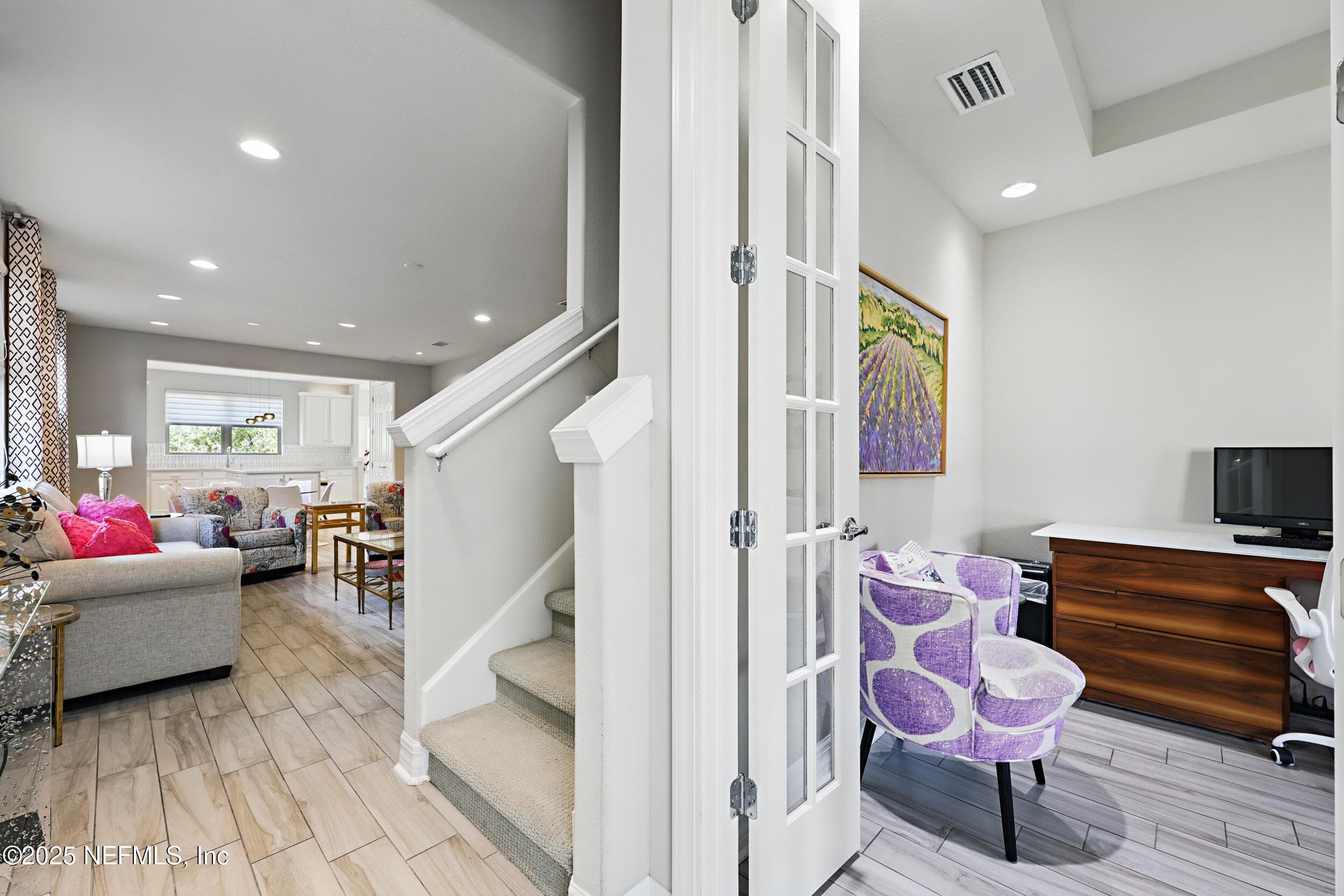 Main level hallway and den — Open layout connecting the living area, carpeted staircase, and first-floor den with French doors. Wood-look tile flooring runs through the main level with recessed lighting overhead. — 92 CANOPY OAK Lane, Ponte Vedra, FL 32081