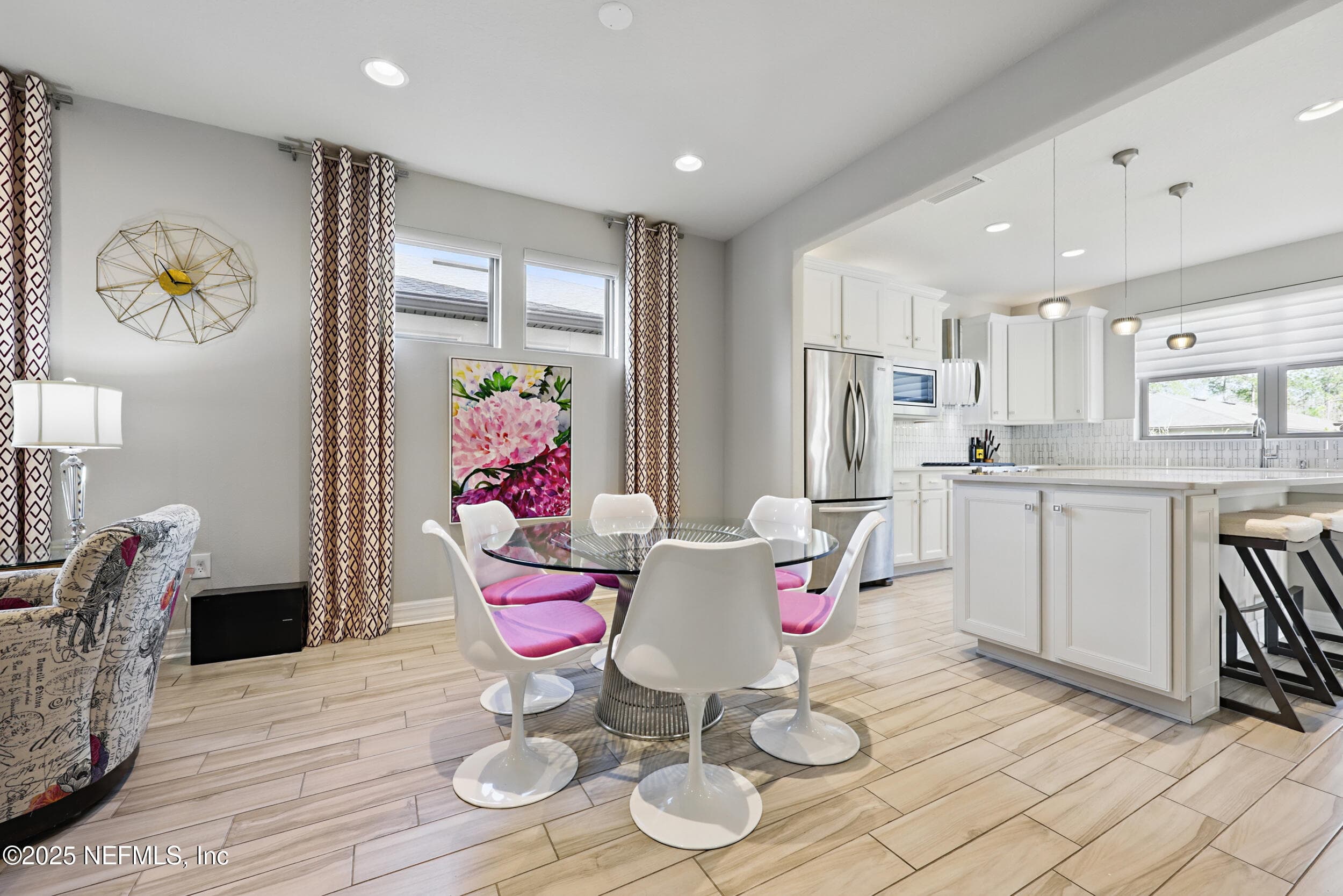 Dining area and kitchen — Open-concept dining area flowing into the kitchen with white shaker cabinetry, stainless steel French door refrigerator, tile backsplash, pendant lighting over the island, and wood-look tile flooring throughout. — 92 CANOPY OAK Lane, Ponte Vedra, FL 32081
