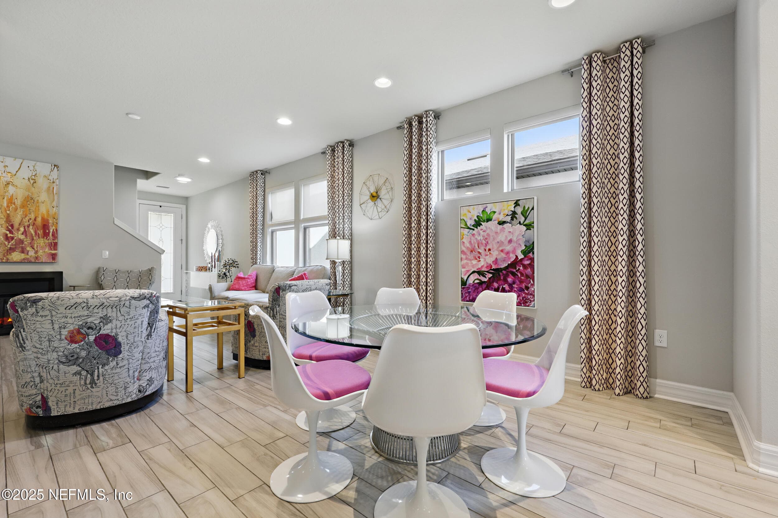 Dining area (toward living room) — Dining space open to the living room with multiple windows, custom curtain panels, recessed lighting, wood-look tile flooring, and views through to the fireplace and foyer. — 92 CANOPY OAK Lane, Ponte Vedra, FL 32081