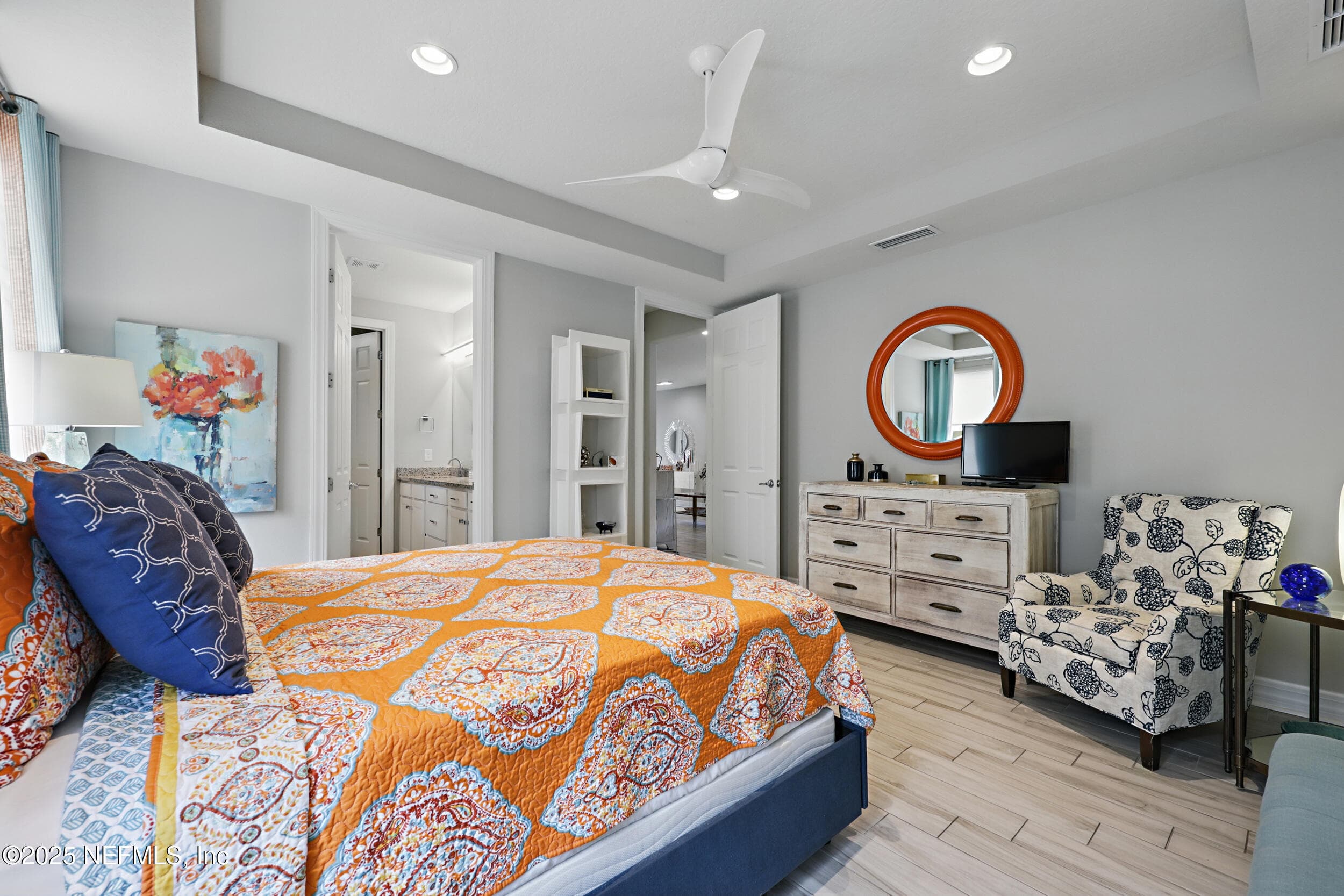 Primary bedroom (closet and bath view) — Primary bedroom with tray ceiling, modern ceiling fan, recessed lighting, wood-look tile flooring, walk-in closet with built-in shelving, and en-suite bathroom access. Double-door closet provides additional storage. — 92 CANOPY OAK Lane, Ponte Vedra, FL 32081