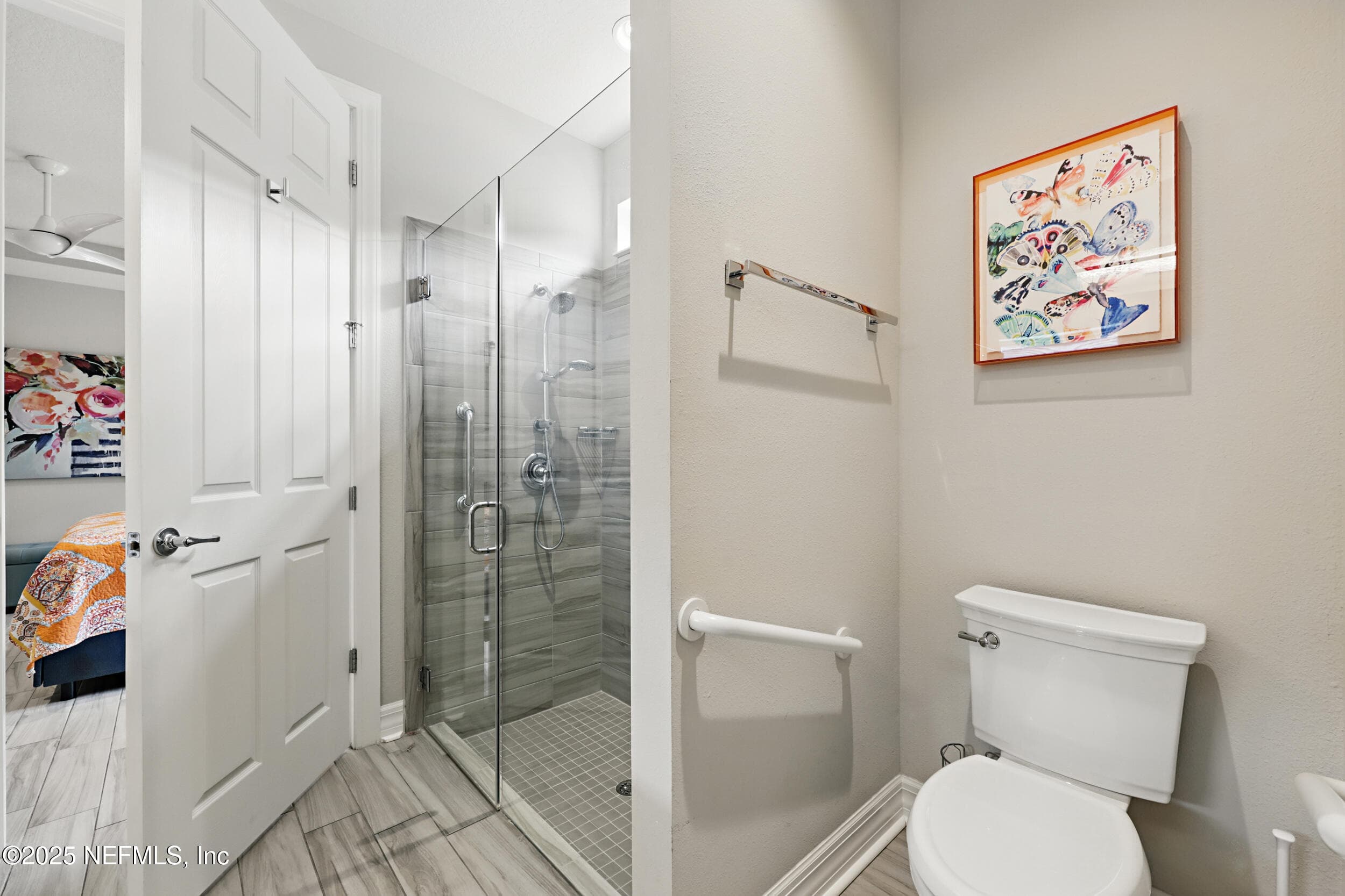 Primary bathroom (shower and water closet) — Primary bath with frameless glass walk-in shower, gray wood-look tile surround, handheld showerhead with slide bar, chrome fixtures, grab bars, and private water closet. — 92 CANOPY OAK Lane, Ponte Vedra, FL 32081