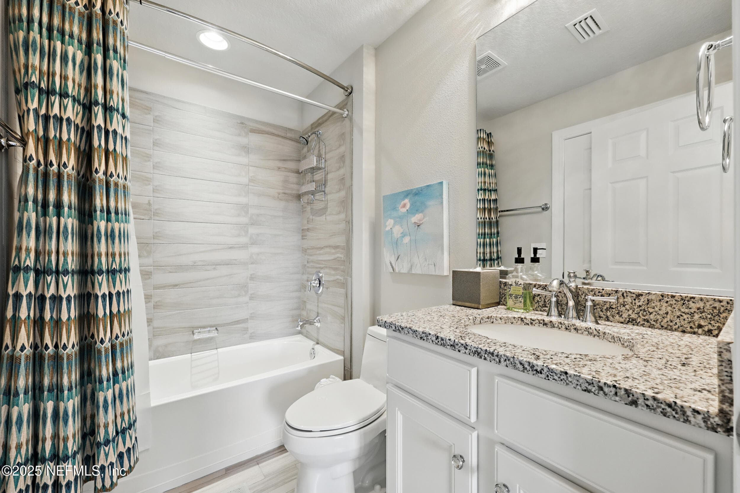 Third bathroom (second floor) — Second-floor full bathroom with tub-shower combo, wood-look tile surround, granite vanity countertop, white shaker cabinet, framed mirror, chrome fixtures, and curved shower rod. — 92 CANOPY OAK Lane, Ponte Vedra, FL 32081