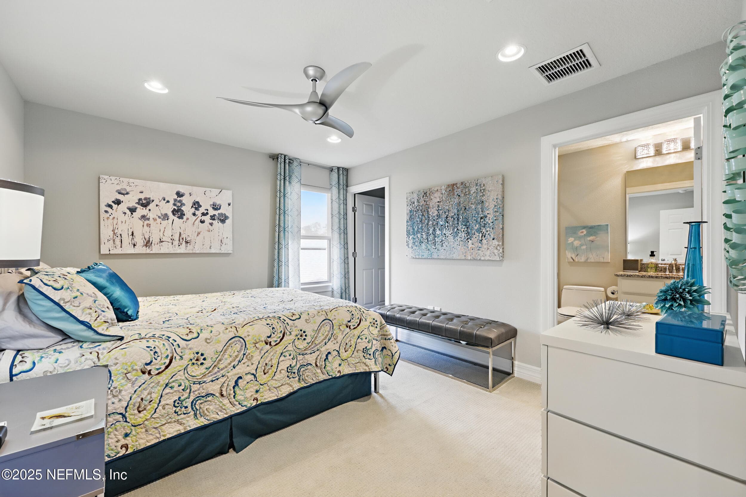 Third bedroom (second floor) — Second-floor bedroom with carpet flooring, modern three-blade ceiling fan, recessed lighting, window with custom curtain panel, closet, and en-suite bathroom access with granite vanity visible through the doorway. — 92 CANOPY OAK Lane, Ponte Vedra, FL 32081