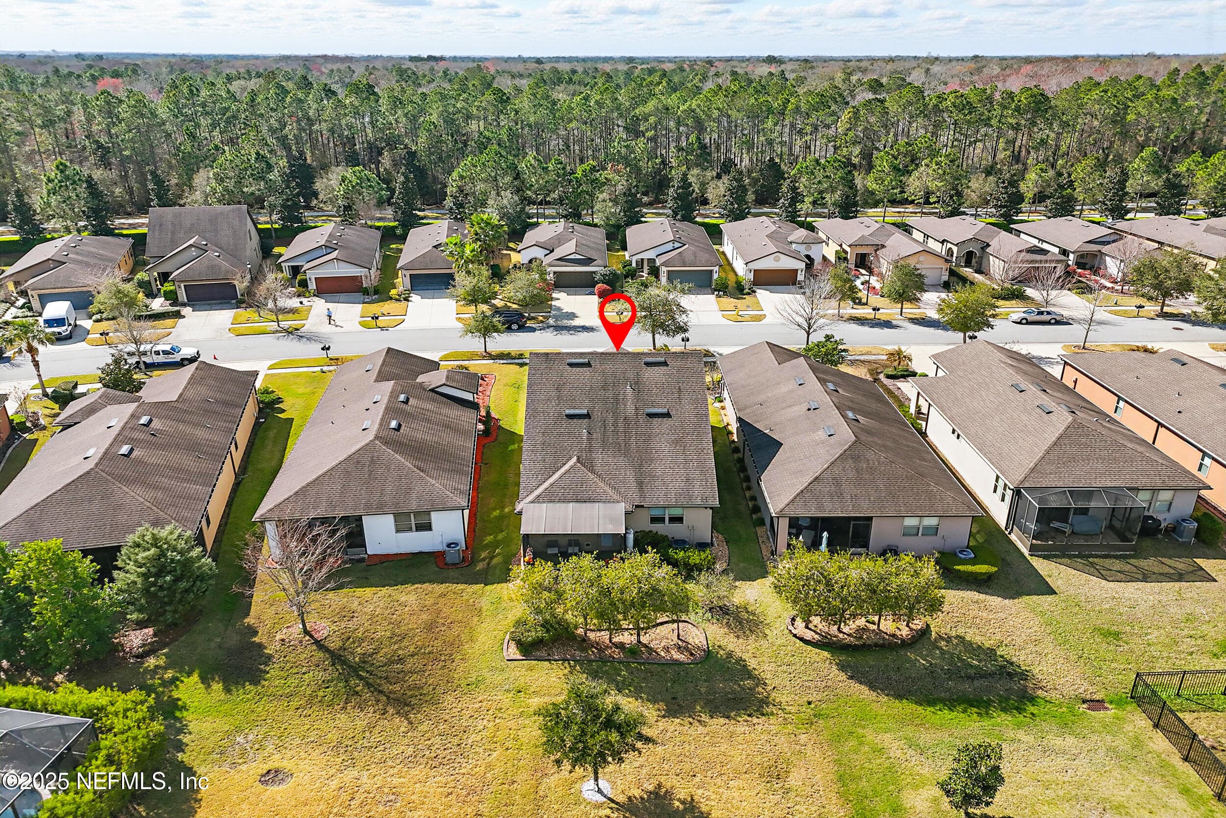 Aerial (rear view) — Drone view of 92 Canopy Oak Lane showing the two-story stucco home with screened lanai, landscaped backyard with mature trees, and preserve tree line backing to the rear of the property in Del Webb Ponte Vedra. — 92 CANOPY OAK Lane, Ponte Vedra, FL 32081