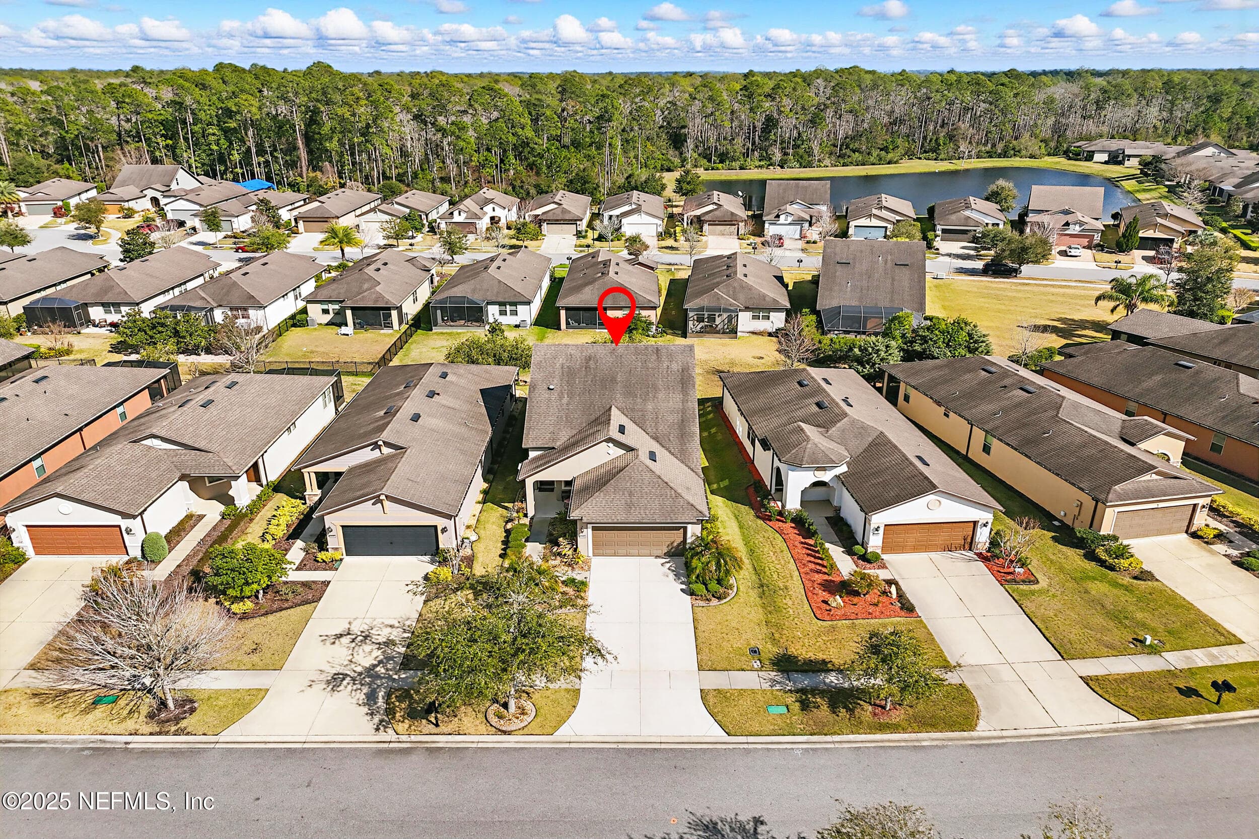 Aerial (front view) — Drone view from the front showing the home on Canopy Oak Lane in Del Webb Ponte Vedra with two-car garage, tropical landscaping, community pond, and preserve views. Sidewalk-lined streets and neighboring homes visible throughout the community. — 92 CANOPY OAK Lane, Ponte Vedra, FL 32081