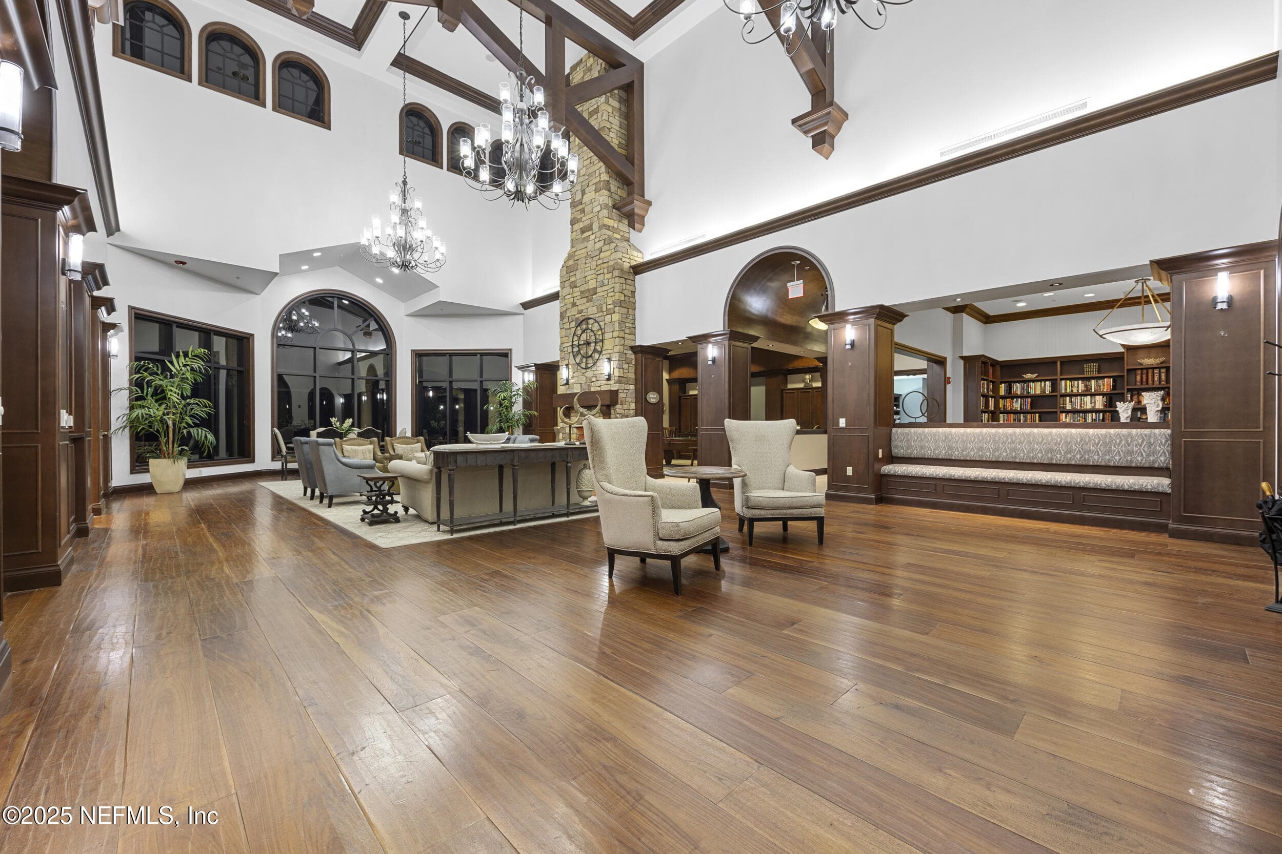 Anastasia Clubhouse grand lobby — Grand lobby inside the 37,000 sq ft Anastasia Clubhouse with soaring vaulted ceiling, exposed wood beam trusses, crystal chandeliers, floor-to-ceiling stone fireplace, hardwood flooring, arched windows, and library with built-in bookshelves. — 92 CANOPY OAK Lane, Ponte Vedra, FL 32081