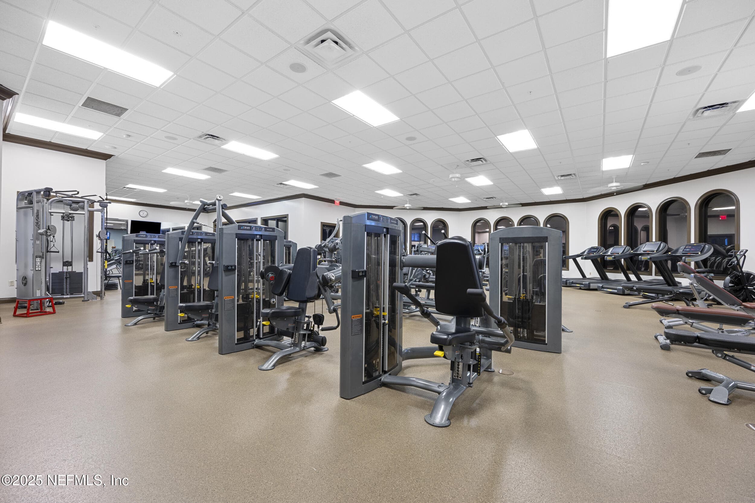 Anastasia Clubhouse fitness center (strength) — Fitness center inside the Anastasia Clubhouse with Life Fitness strength training machines, weight benches, arched windows, and open floor plan. Part of the 37,000 sq ft clubhouse in Del Webb Ponte Vedra. — 92 CANOPY OAK Lane, Ponte Vedra, FL 32081