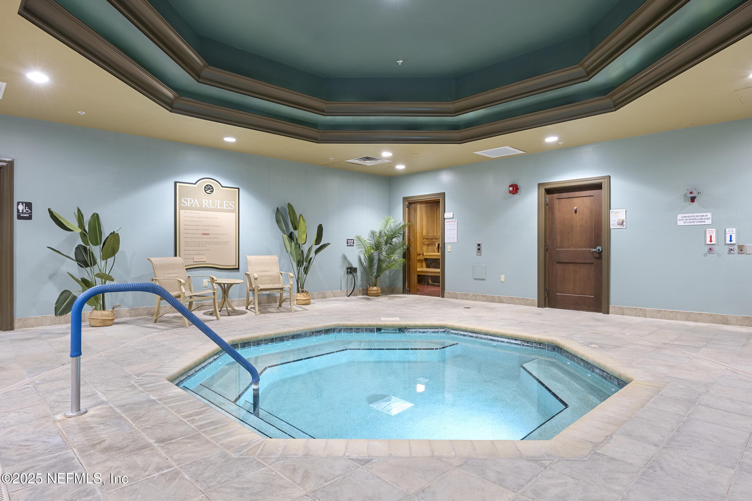 Anastasia Clubhouse indoor spa (alternate angle) — Indoor heated spa with handrail entry, sauna and steam room doors visible, tile deck, octagonal ceiling detail, and relaxation seating area inside the 37,000 sq ft Anastasia Clubhouse. — 92 CANOPY OAK Lane, Ponte Vedra, FL 32081
