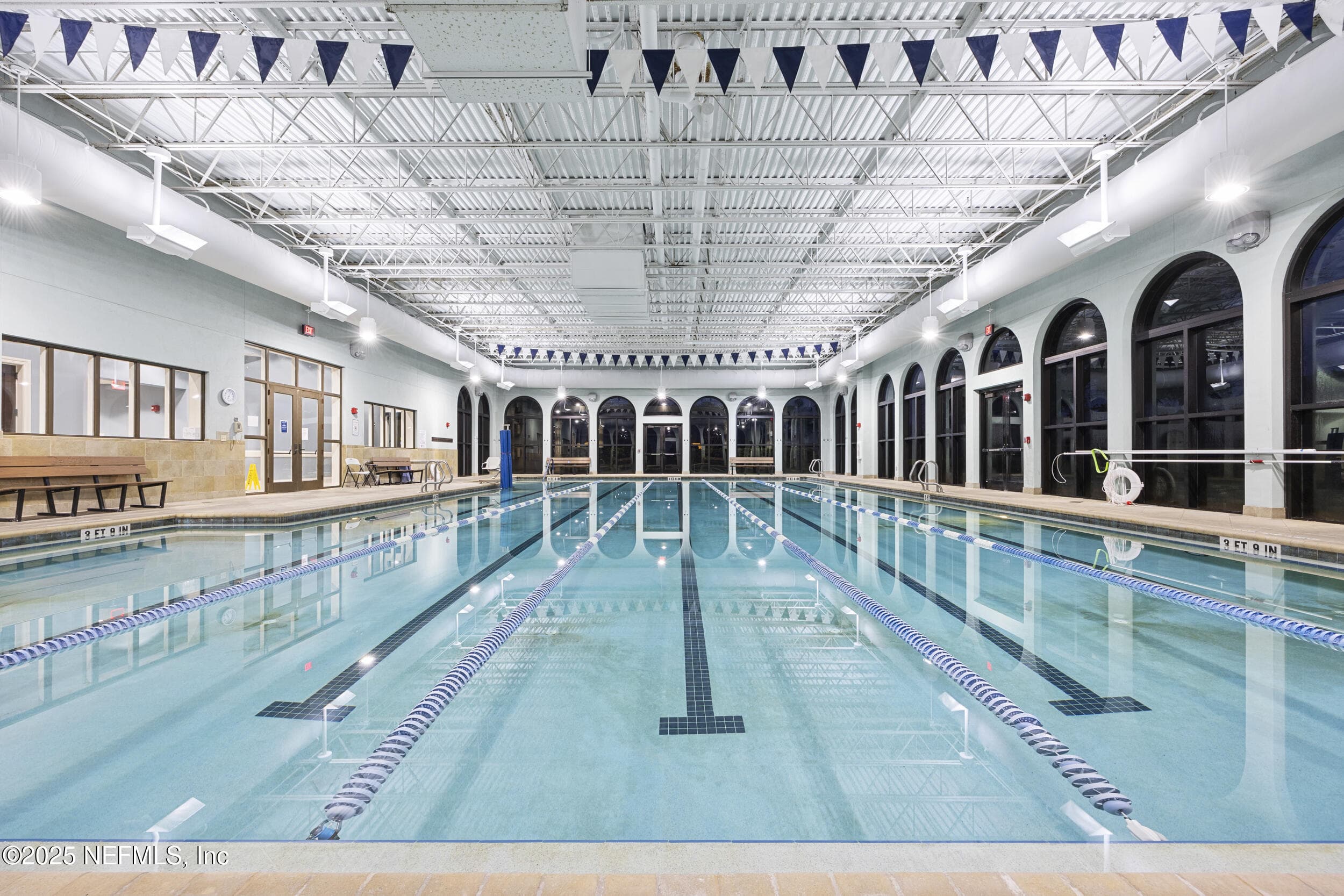 Anastasia Clubhouse indoor lap pool (lane view) — Indoor lap pool with multiple swim lanes, lane dividers, arched windows along both sides, high ceiling with exposed trusses, and bench seating inside the Anastasia Clubhouse. — 92 CANOPY OAK Lane, Ponte Vedra, FL 32081