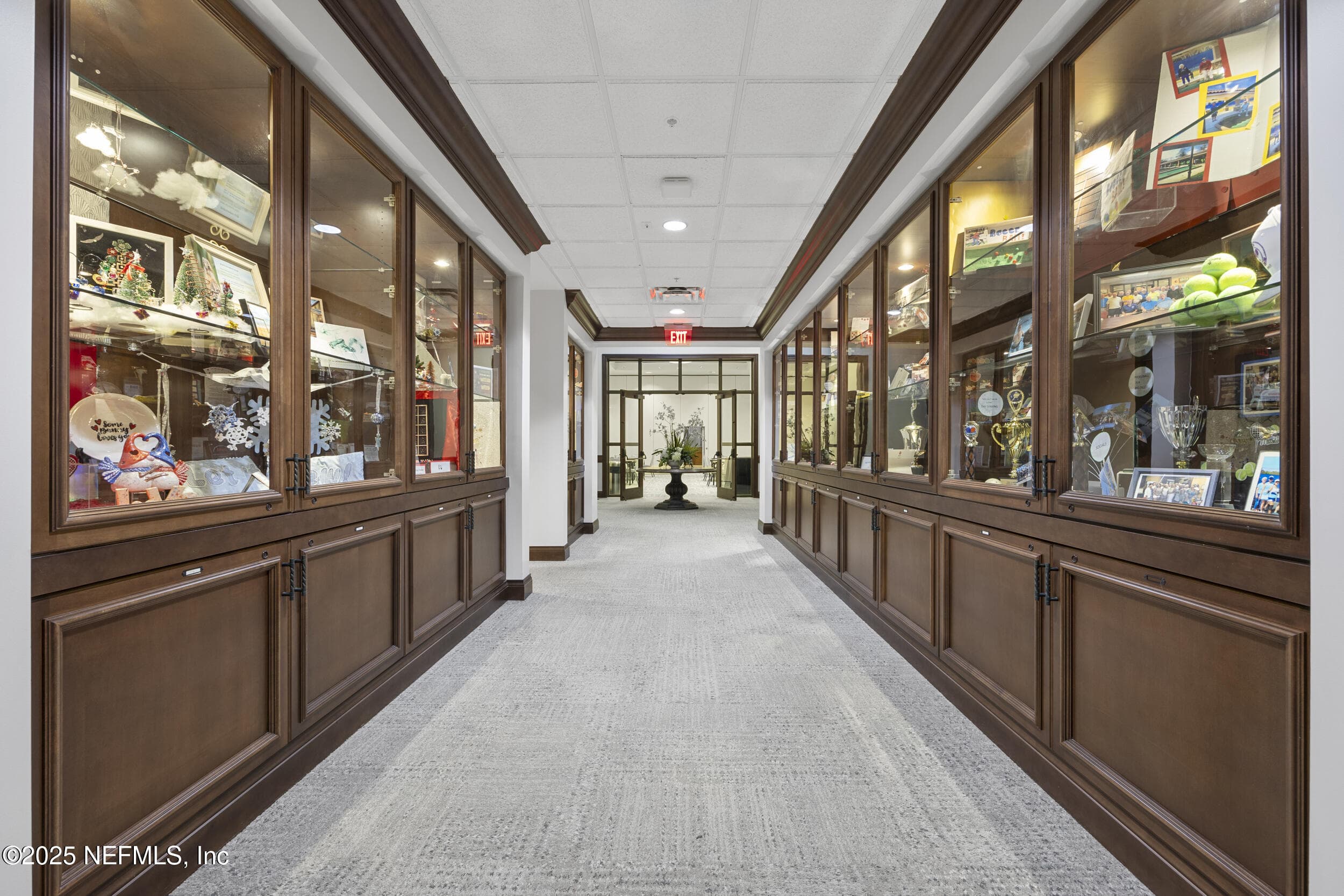 Anastasia Clubhouse display corridor — Clubhouse corridor with glass-front display cabinets showcasing resident artwork, trophies, and community memorabilia inside the Anastasia Clubhouse at Del Webb Ponte Vedra. — 92 CANOPY OAK Lane, Ponte Vedra, FL 32081