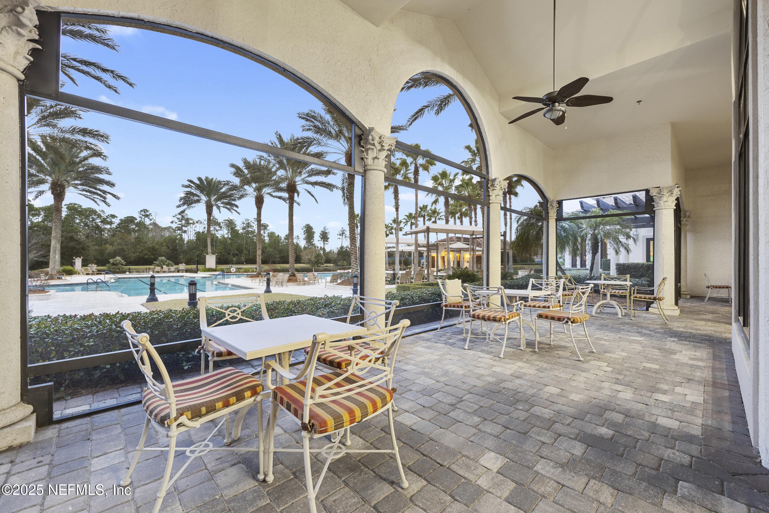 Anastasia Clubhouse covered outdoor patio — Covered outdoor patio with paver deck, arched openings with Corinthian columns, ceiling fans, dining tables, and poolside views adjacent to the Anastasia Clubhouse at Del Webb Ponte Vedra. — 92 CANOPY OAK Lane, Ponte Vedra, FL 32081