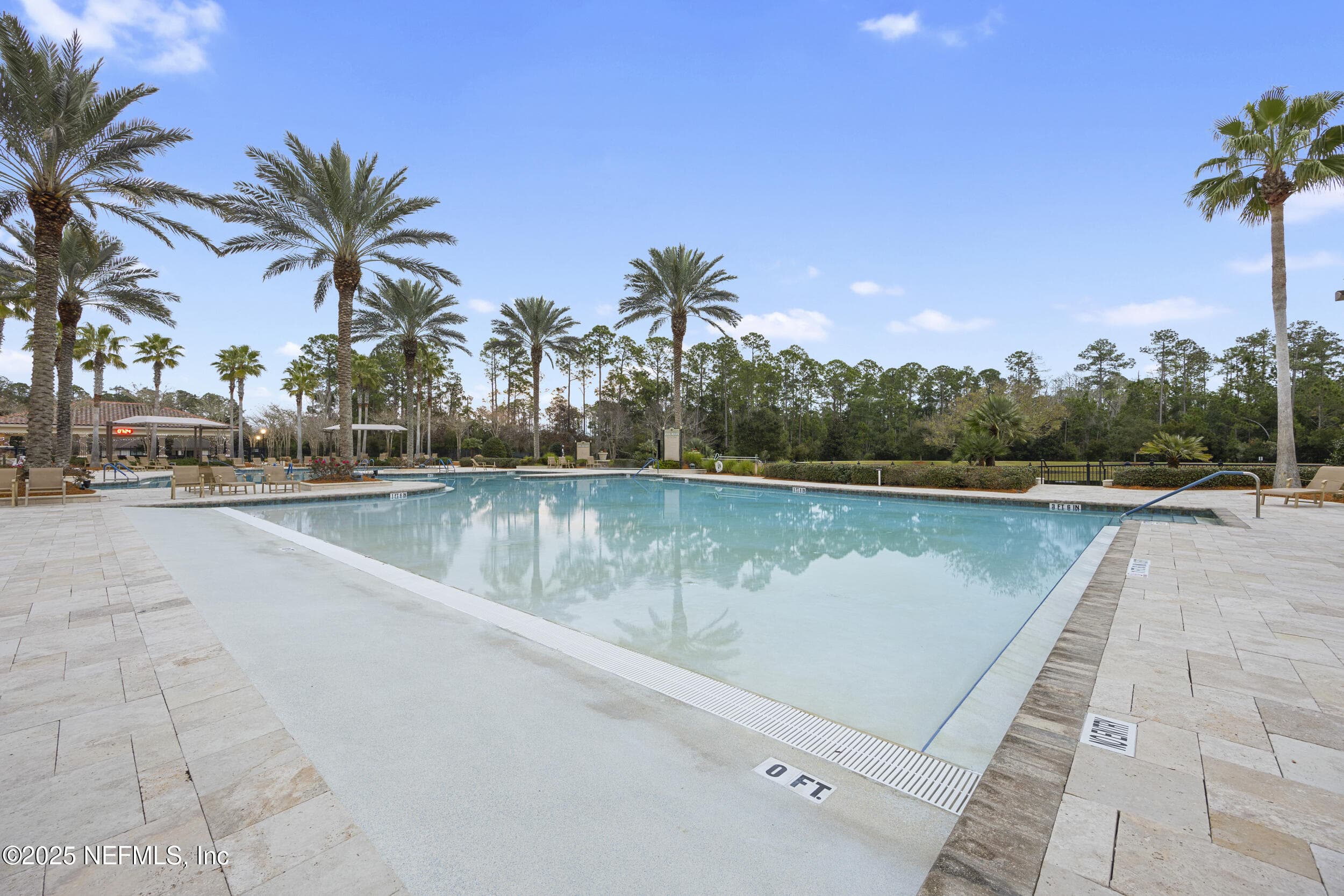 Del Webb Ponte Vedra outdoor beach entry pool — Outdoor beach entry pool with zero-depth entry, travertine paver deck, palm-lined surroundings, cabana pavilion, and preserve tree line at Del Webb Ponte Vedra. — 92 CANOPY OAK Lane, Ponte Vedra, FL 32081
