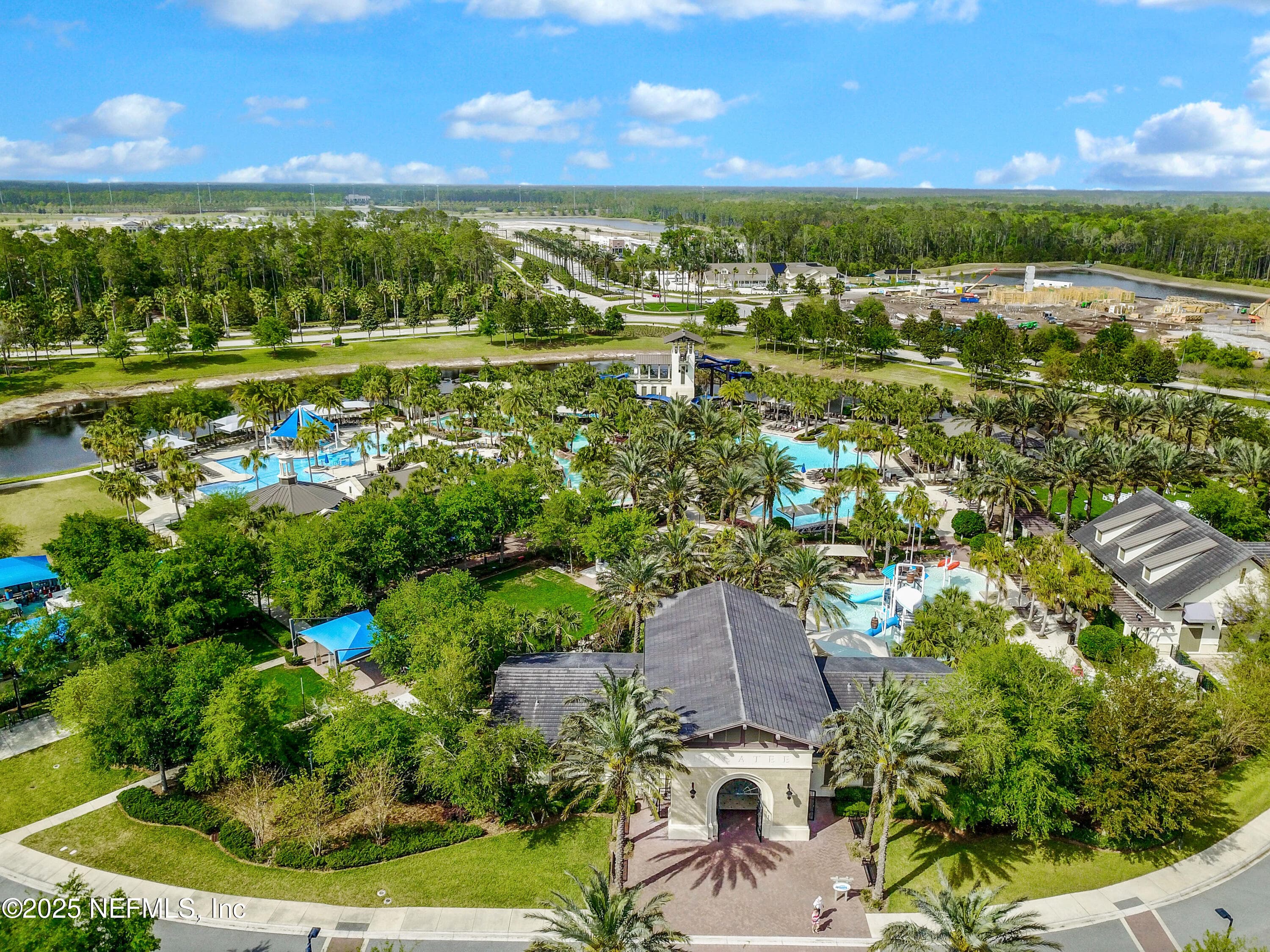 Nocatee Splash Water Park (aerial close) — Aerial view of the Nocatee Splash Water Park showing dual high-speed waterslides, multiple resort-style pools, lazy river, splash areas, cabanas, covered pavilions, and lush tropical landscaping throughout the park. — 92 CANOPY OAK Lane, Ponte Vedra, FL 32081