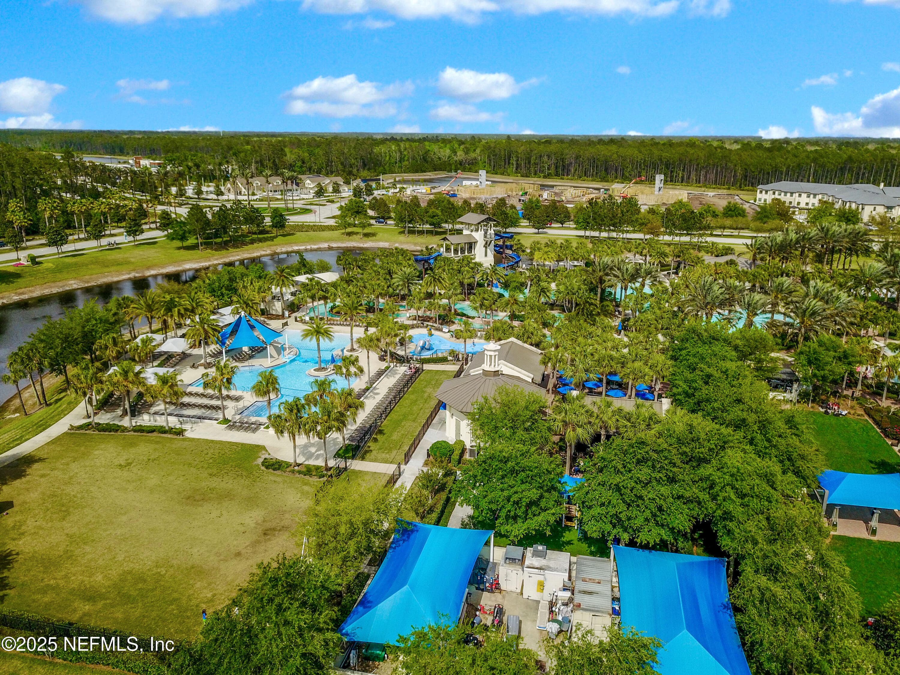 Nocatee Splash Water Park and event lawn (aerial) — Wide aerial showing the full Nocatee Splash Water Park complex with waterslides, splash pools, lazy river, event lawn for Food Truck Fridays and farmers markets, shade tent pavilions, and waterfront setting in Ponte Vedra, FL. — 92 CANOPY OAK Lane, Ponte Vedra, FL 32081