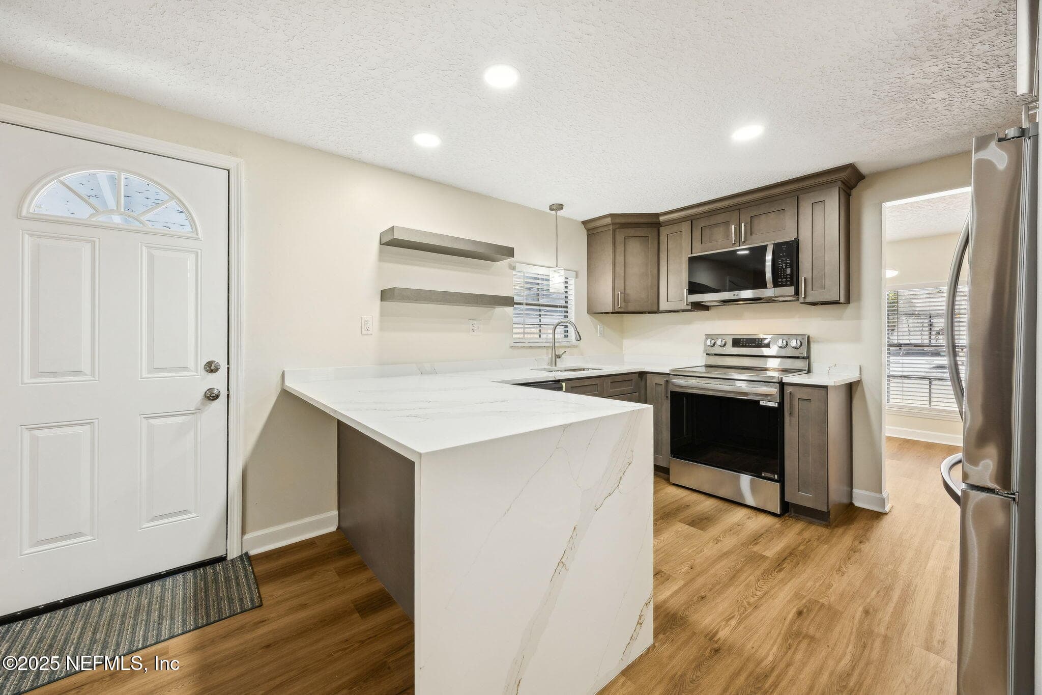 Kitchen Photo #2 Designer grade quartz with waterfall look over breakfast bar — 7611 MC COWAN Drive, Jacksonville, FL 32244