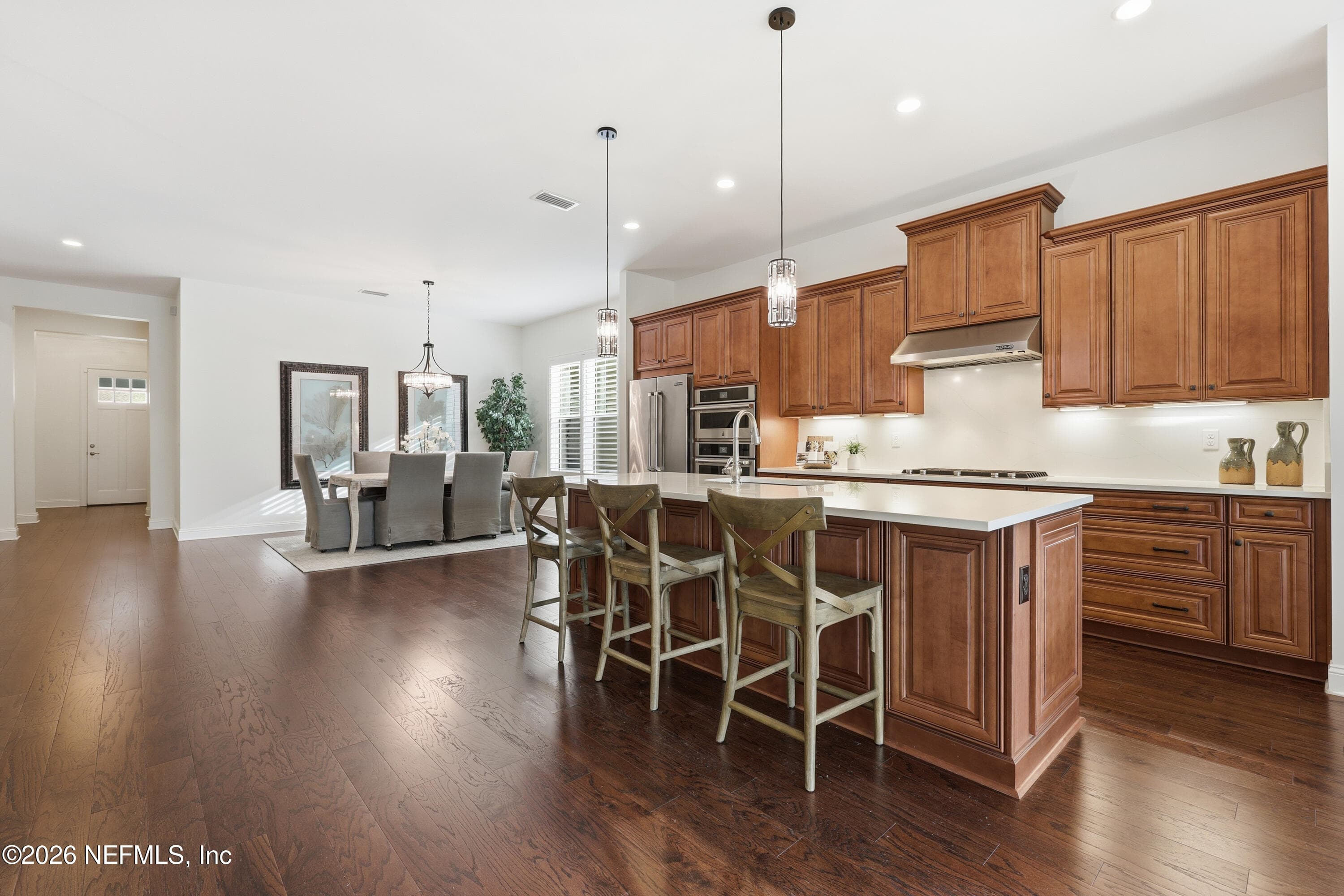 Kitchen open to living area with spacious island, pendant lights, and continuous hardwood flooring. — 568 TIMBER BRIDGE Lane, Atlantic Beach, FL 32233