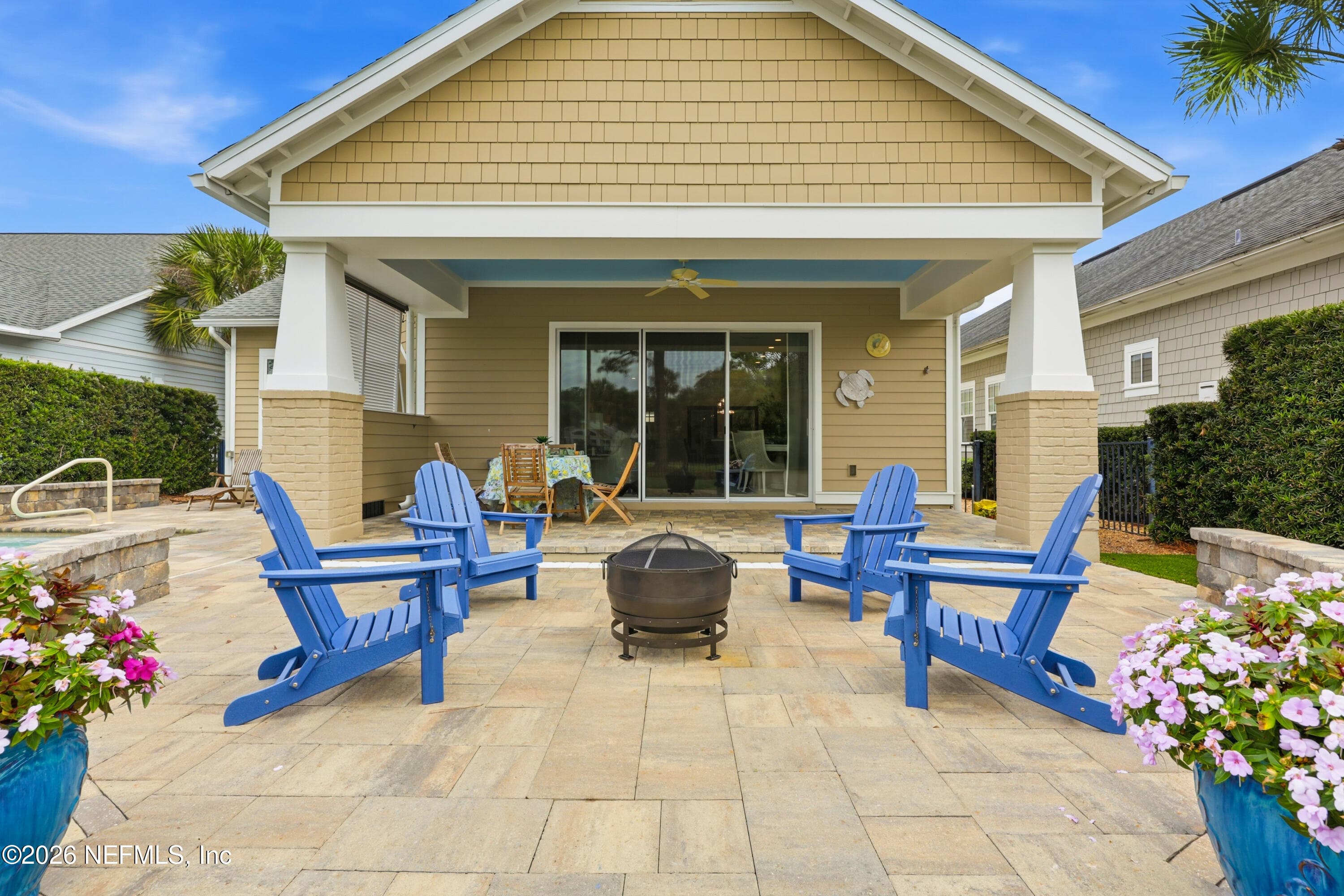 Paver patio seating area with Adirondack chairs and a central fire pit near the home. — 568 TIMBER BRIDGE Lane, Atlantic Beach, FL 32233