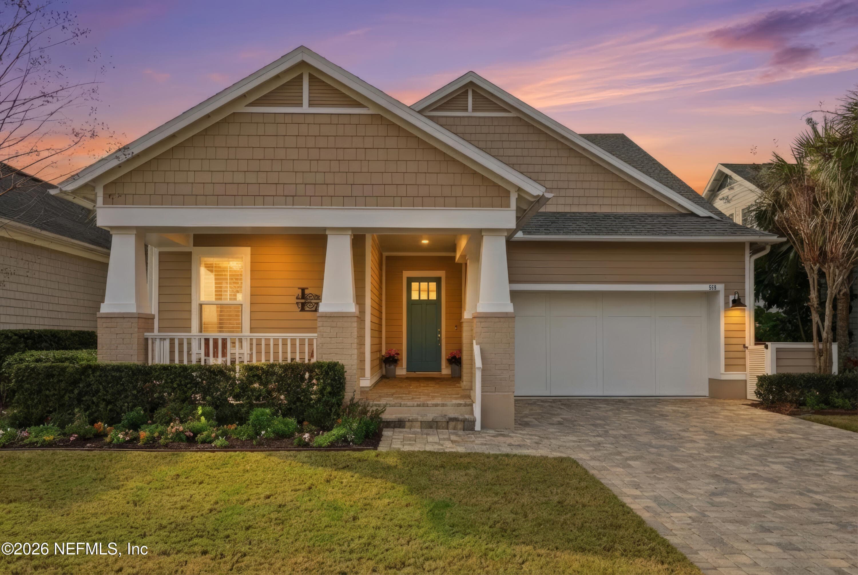 Twilight front exterior shows craftsman-style entry and paver driveway lighting. — 568 TIMBER BRIDGE Lane, Atlantic Beach, FL 32233