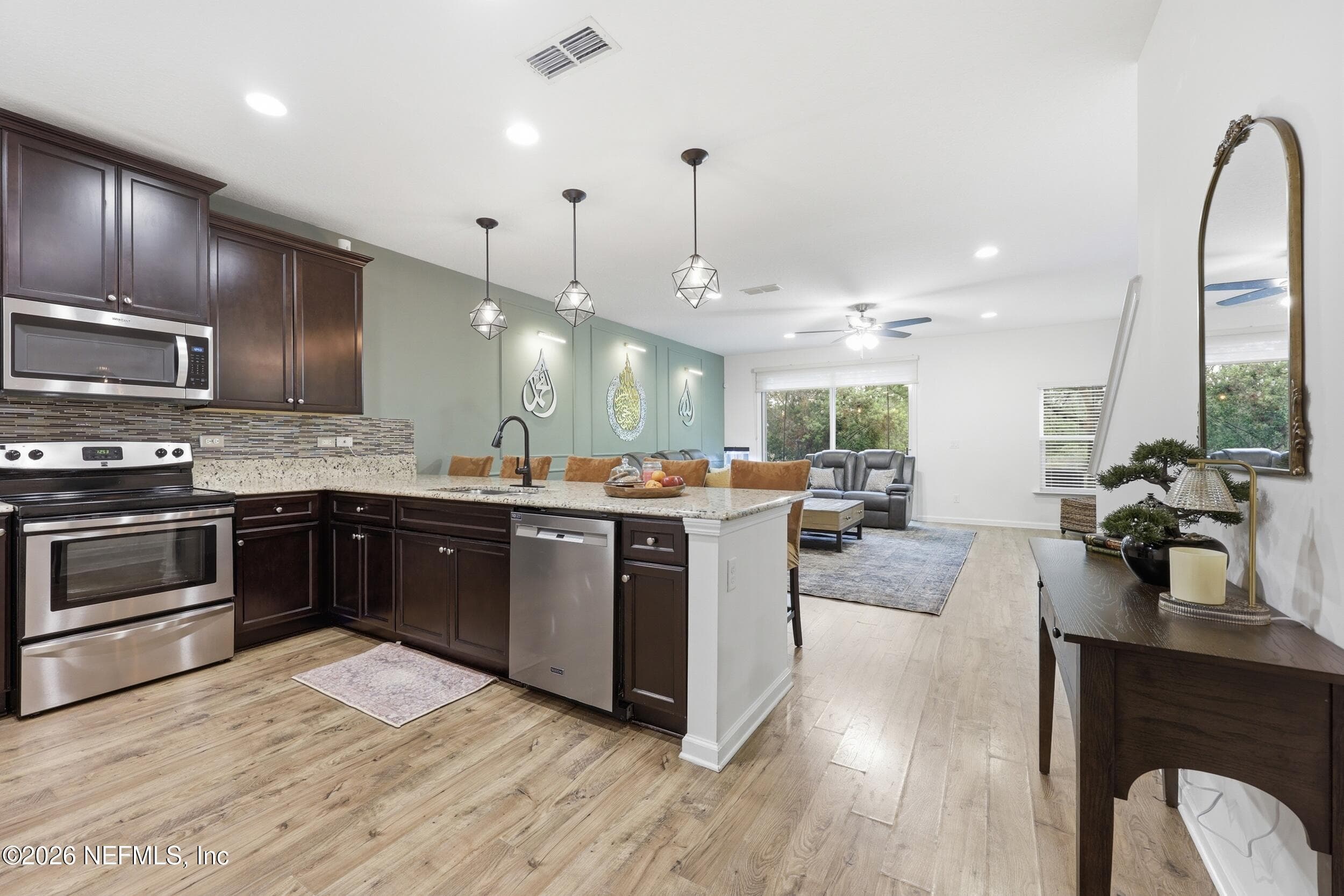 View from the front entry showcasing the open layout with sightlines to the kitchen, living area, and sliding glass doors. — 3650 CRESWICK Circle C, Orange Park, FL 32065