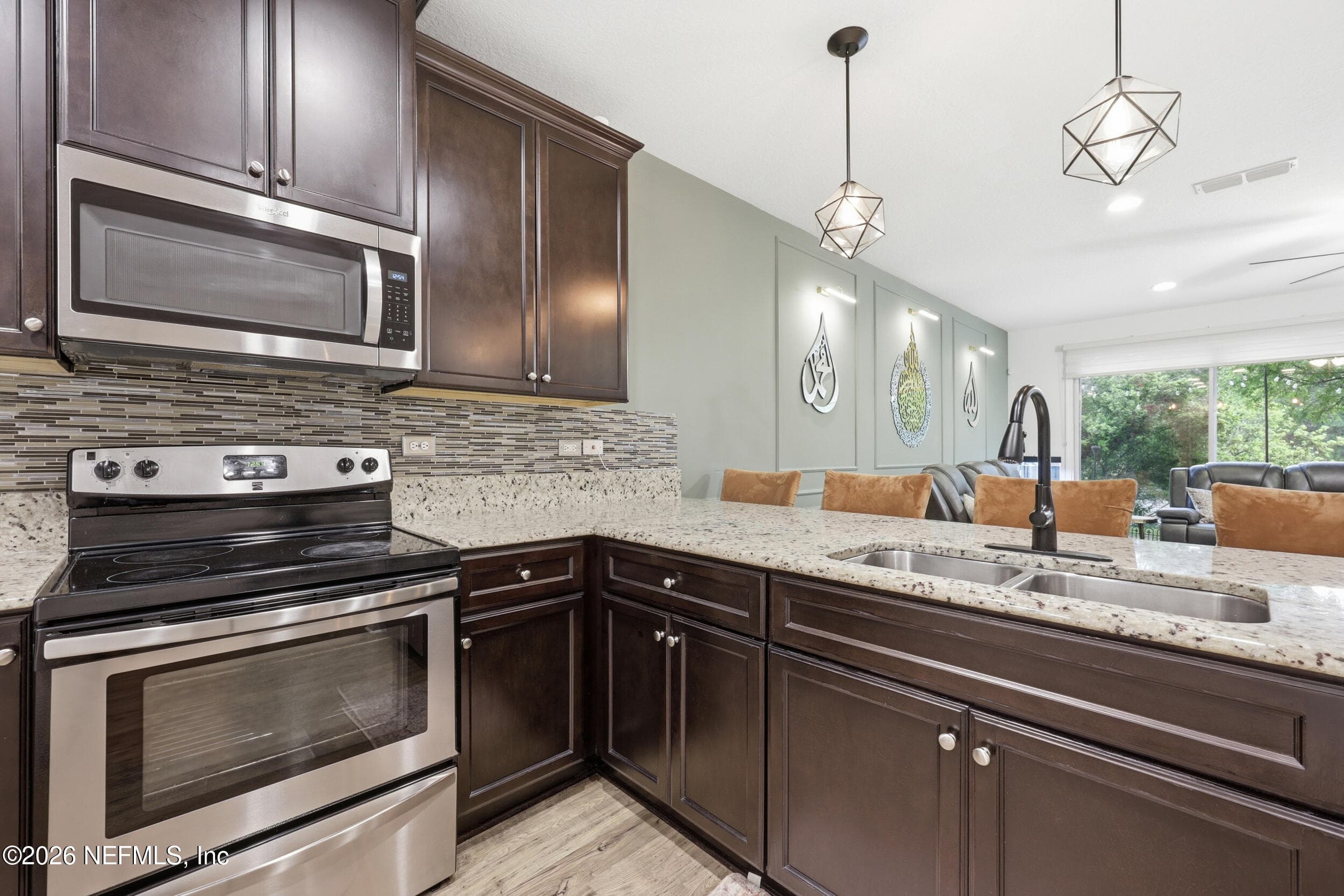 Open kitchen with bar seating, pendant lighting, and a seamless flow into the main living space. — 3650 CRESWICK Circle C, Orange Park, FL 32065
