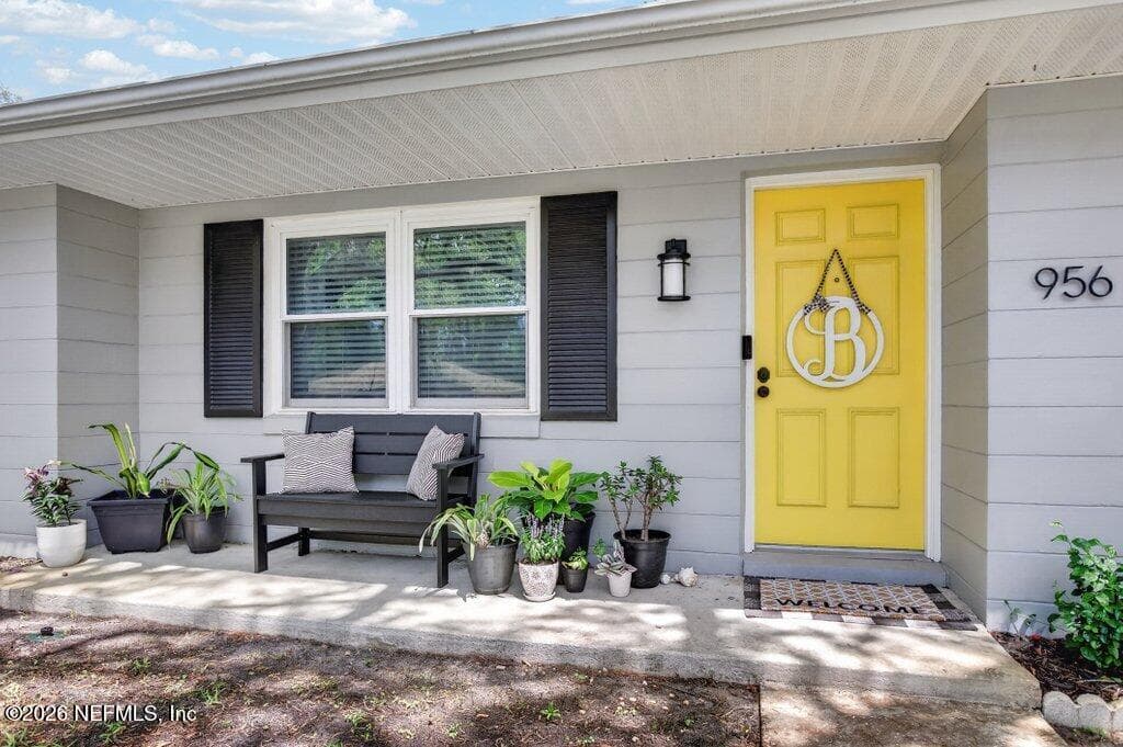 A charming covered entry featuring modern lighting and a vibrant front door that adds a personalized touch to the facade. — 956 ESPINADO Avenue, St. Augustine, FL 32086