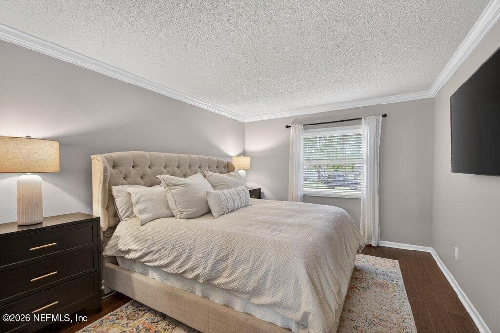 A tranquil bedroom suite finished with soft neutral tones, crown molding, and a large window that provides a peaceful view of the property. — 956 ESPINADO Avenue, St. Augustine, FL 32086