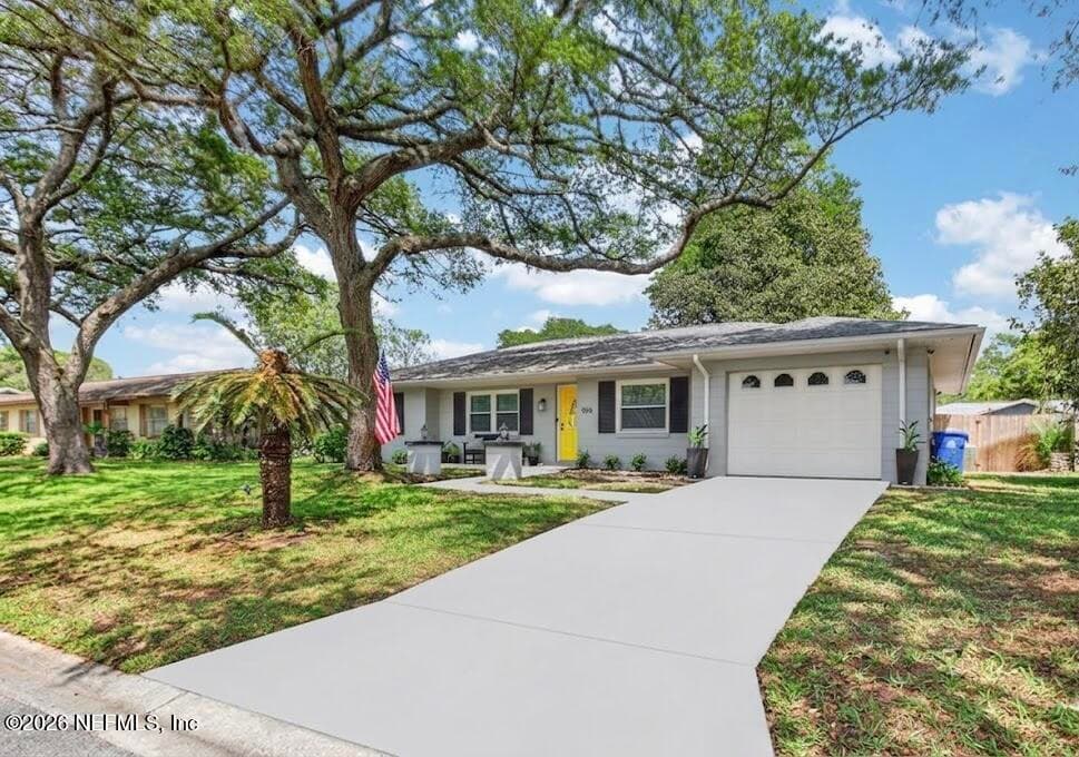 A well-maintained lawn and mature shade trees, complemented by a wide driveway leading to a clean, attached garage. — 956 ESPINADO Avenue, St. Augustine, FL 32086