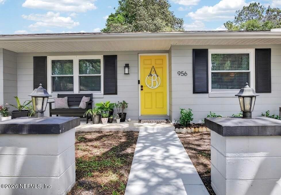 A welcoming front entry featuring a bold yellow door that creates a vibrant focal point against the neutral siding and classic black shutters. — 956 ESPINADO Avenue, St. Augustine, FL 32086