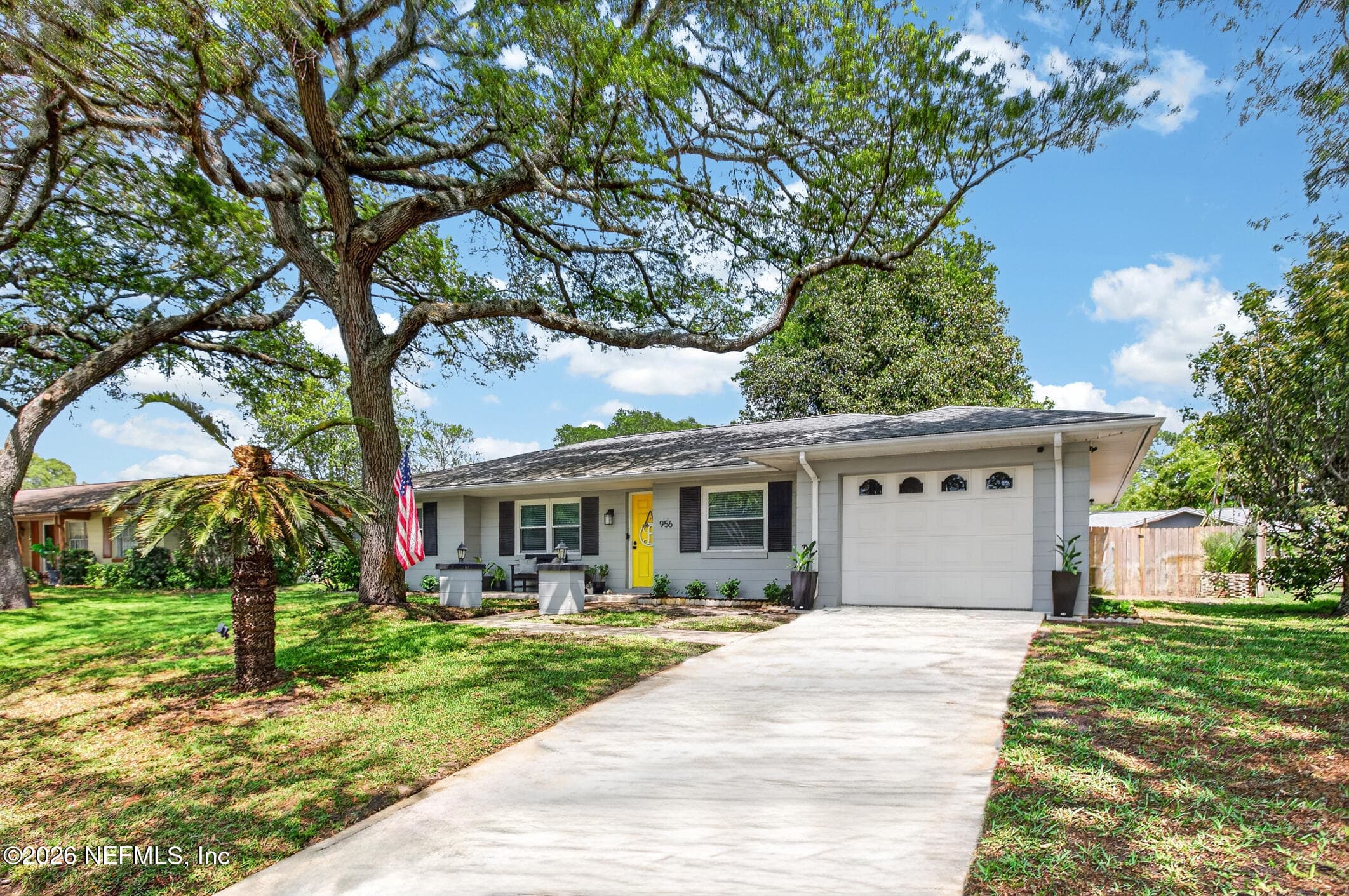 A wide perspective of the property showcasing the deep setback, integrated garage, and the character provided by established oak trees. — 956 ESPINADO Avenue, St. Augustine, FL 32086