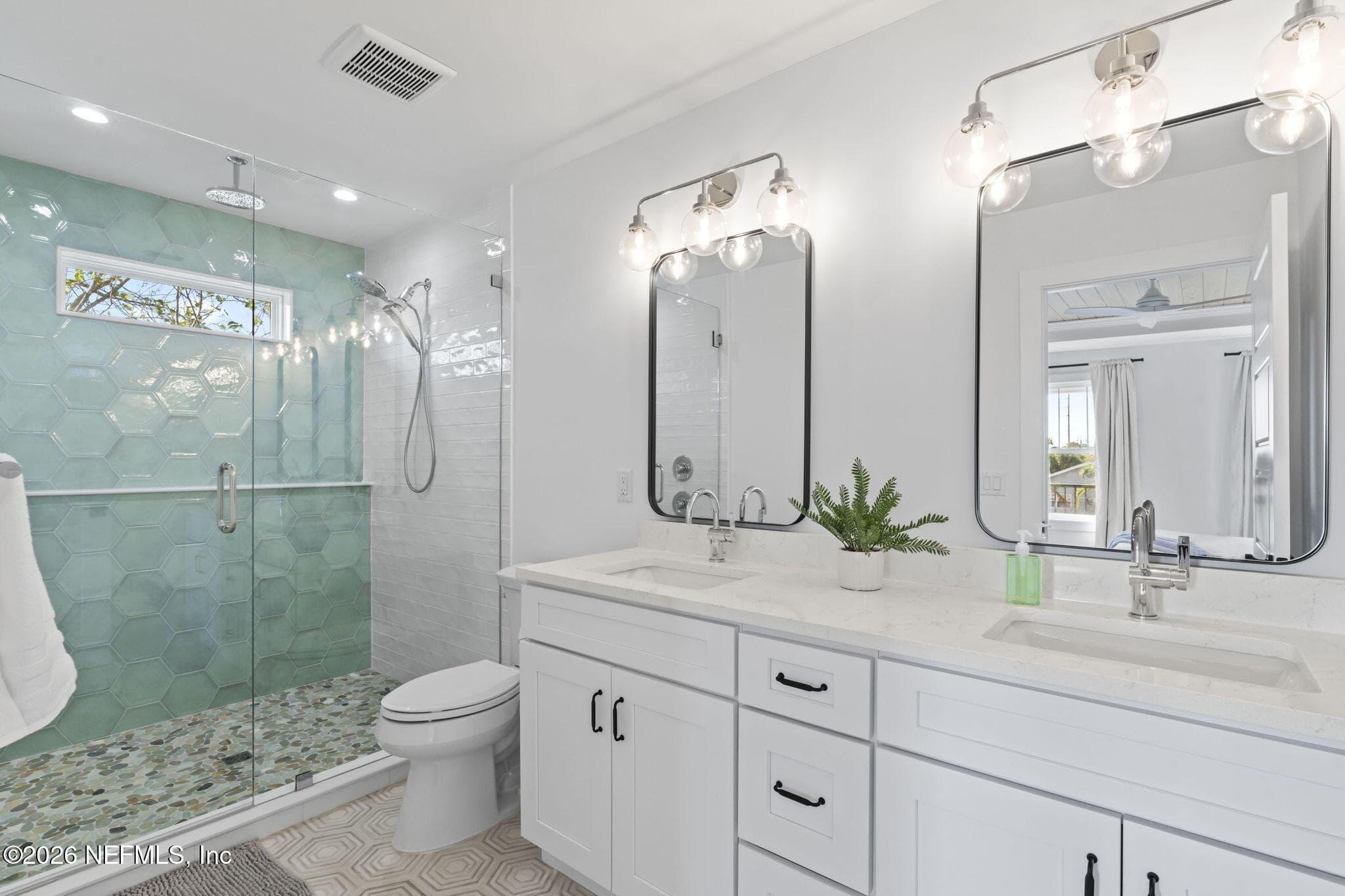 Primary bath with full heavy glass frameless shower enclosure, Schluter waterproofing system, upgraded Moen plumbing fixtures, adult-height vanities and quartz counters — 925 2ND Avenue S, Jacksonville Beach, FL 32250