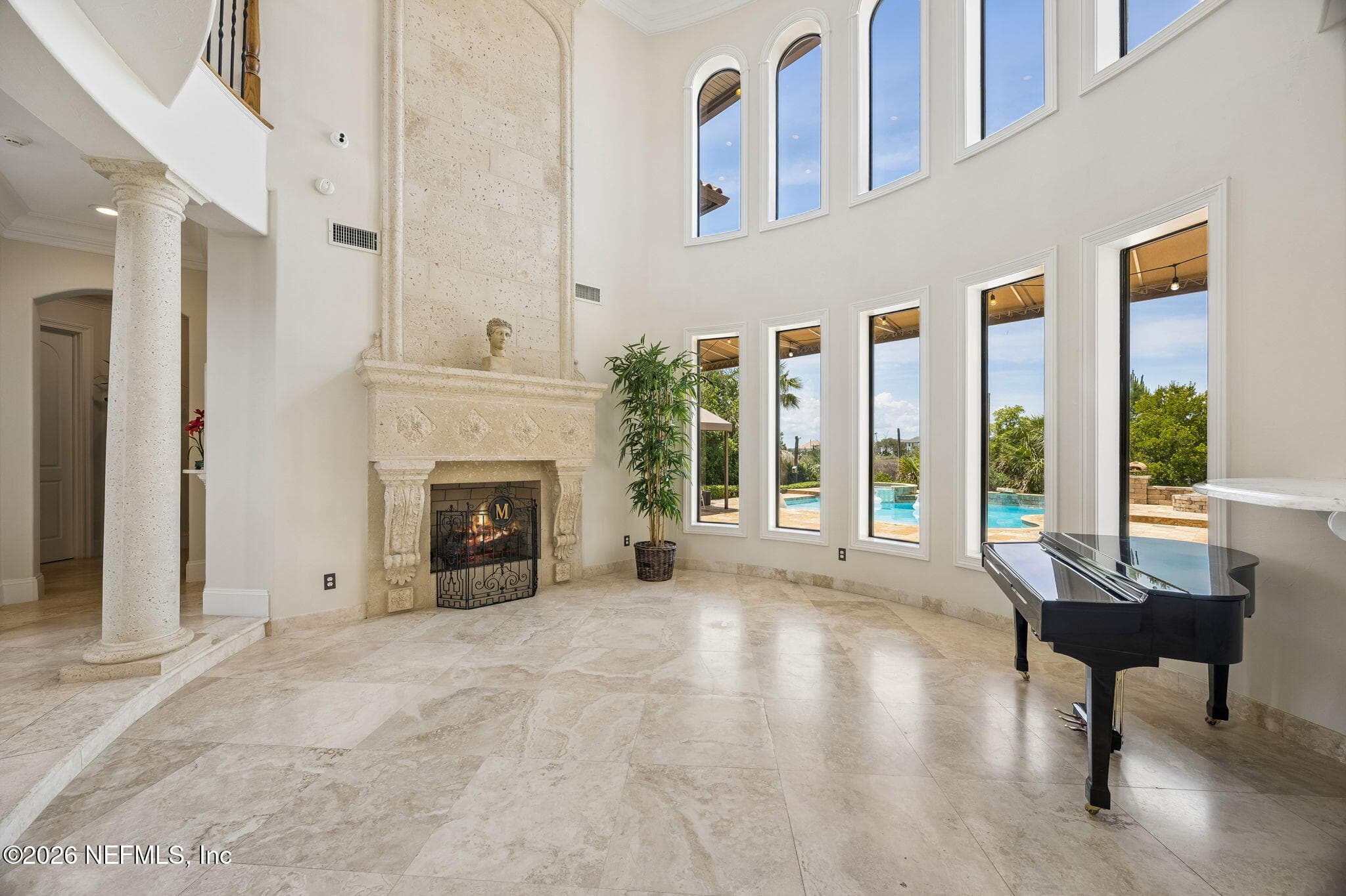 The living room is filled with natural light from dramatic two-story windows, while a stunning fireplace creates a warm and inviting focal point overlooking picturesque views. — 430 ROYAL TERN Road S, Jacksonville Beach, FL 32250