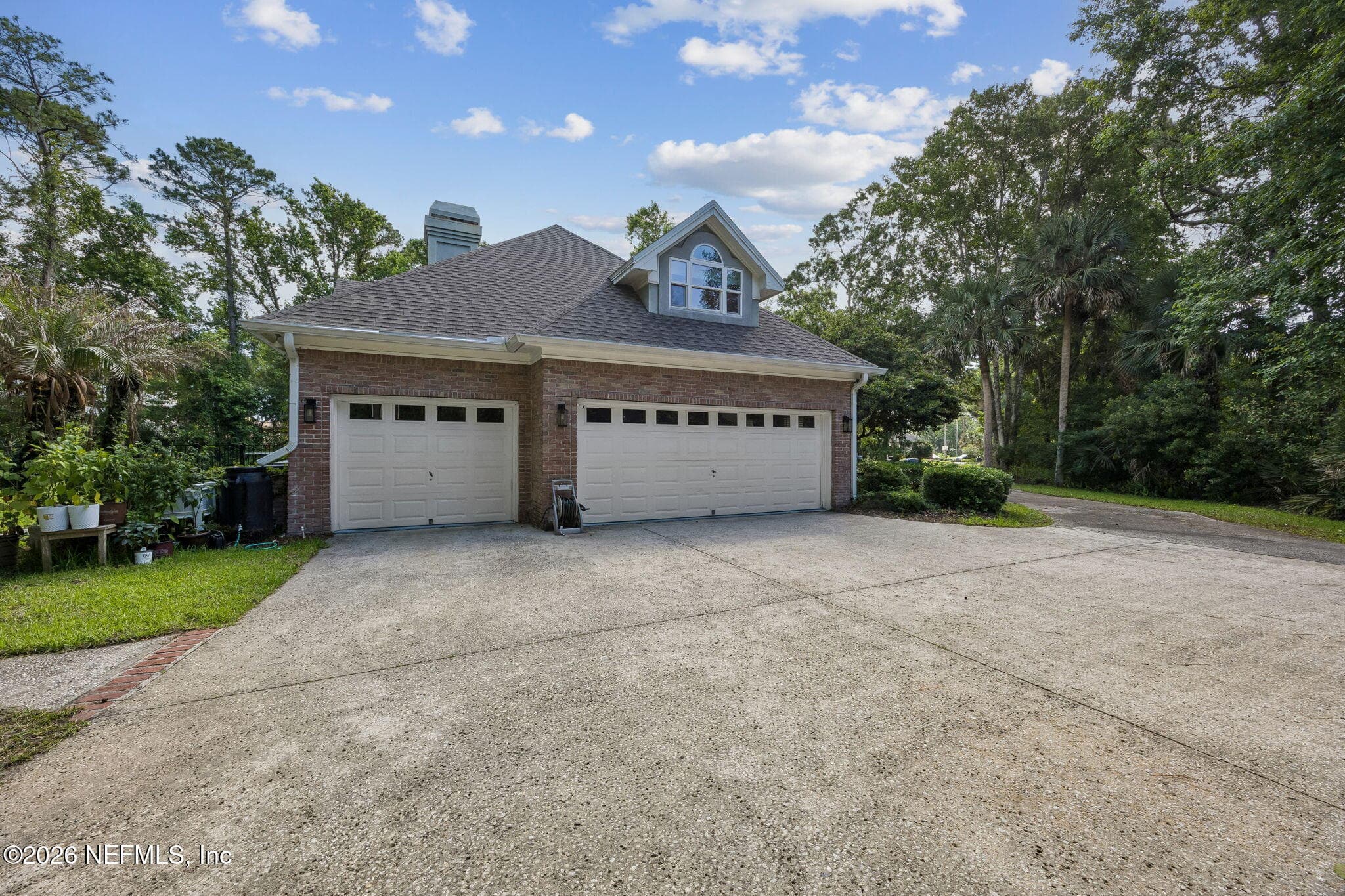 A spacious three-car garage and extended driveway offer ample parking and functionality, all surrounded by lush landscaping and serene natural privacy. — 5070 BENTGRASS Circle, Ponte Vedra Beach, FL 32082