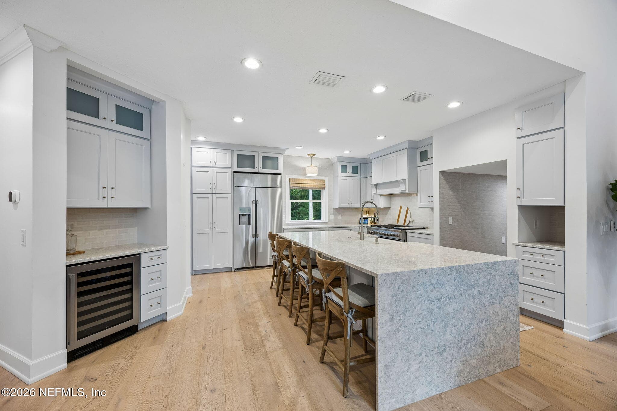 The chef-inspired kitchen features an oversized waterfall island, custom cabinetry, stainless steel appliances, and abundant prep space. — 5070 BENTGRASS Circle, Ponte Vedra Beach, FL 32082
