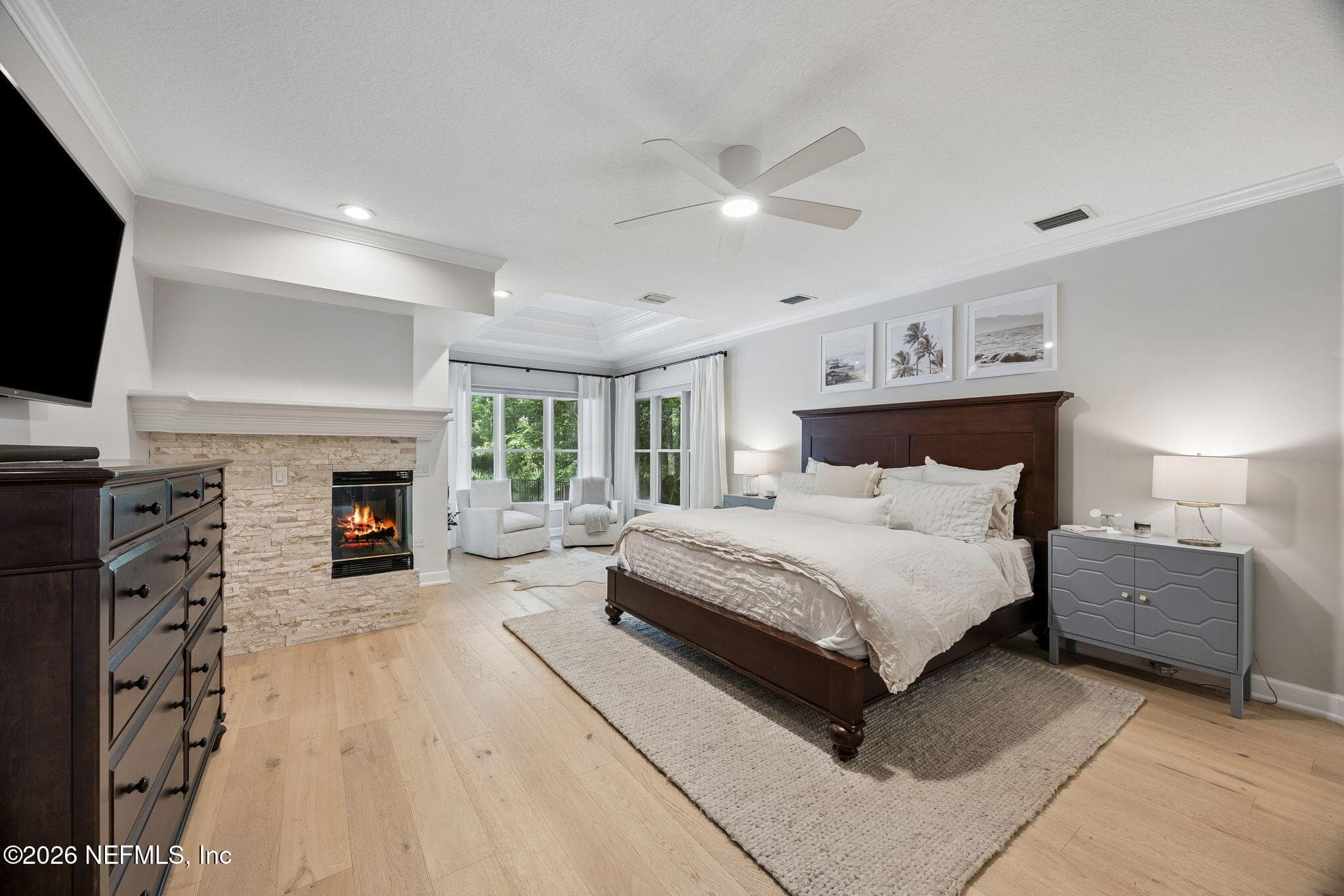 Spacious primary suite featuring warm wood floors, a cozy fireplace, and a serene sitting area surrounded by natural light. — 5070 BENTGRASS Circle, Ponte Vedra Beach, FL 32082