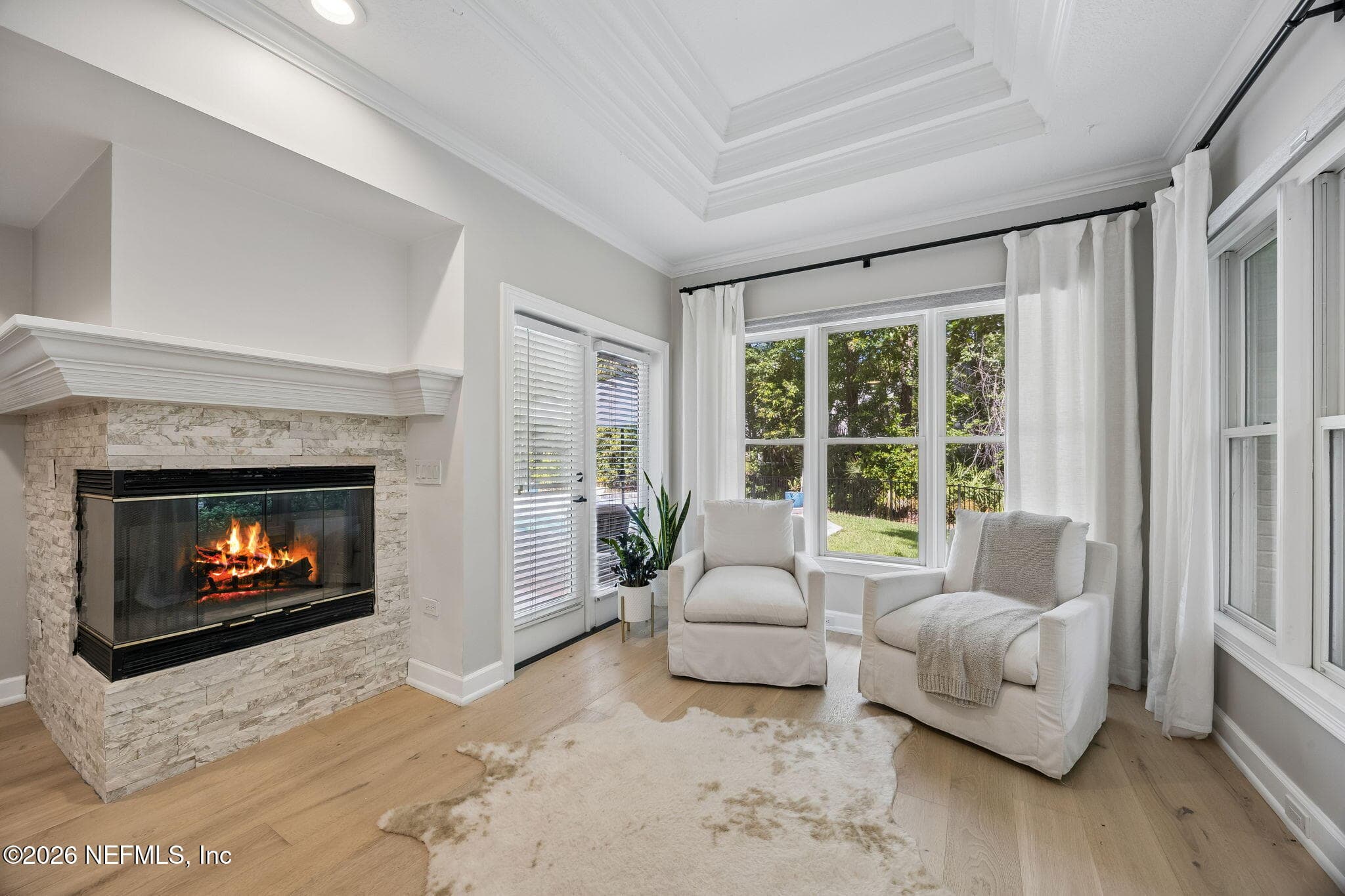 Cozy fireside sitting area with tray ceilings, abundant natural light, and peaceful views. — 5070 BENTGRASS Circle, Ponte Vedra Beach, FL 32082