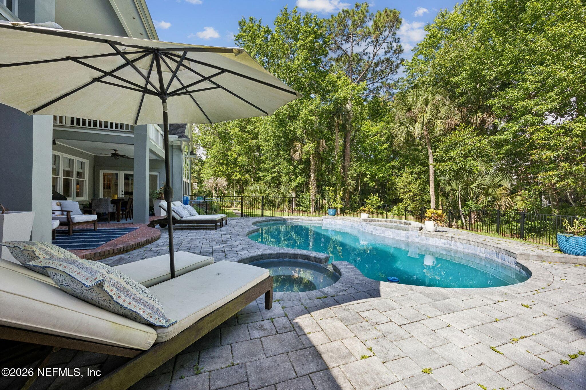Resort-style outdoor oasis with a sparkling pool, expansive paver patio, and tranquil wooded privacy. — 5070 BENTGRASS Circle, Ponte Vedra Beach, FL 32082